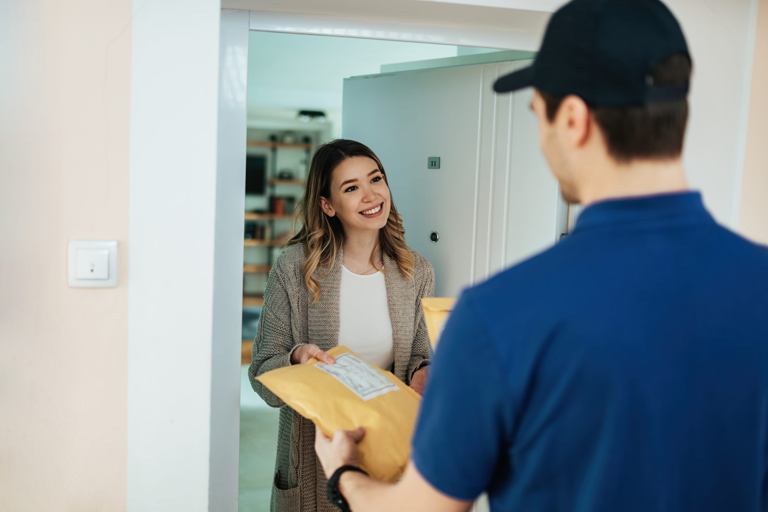 Happy woman taking package from a courier while receiving home delivery.